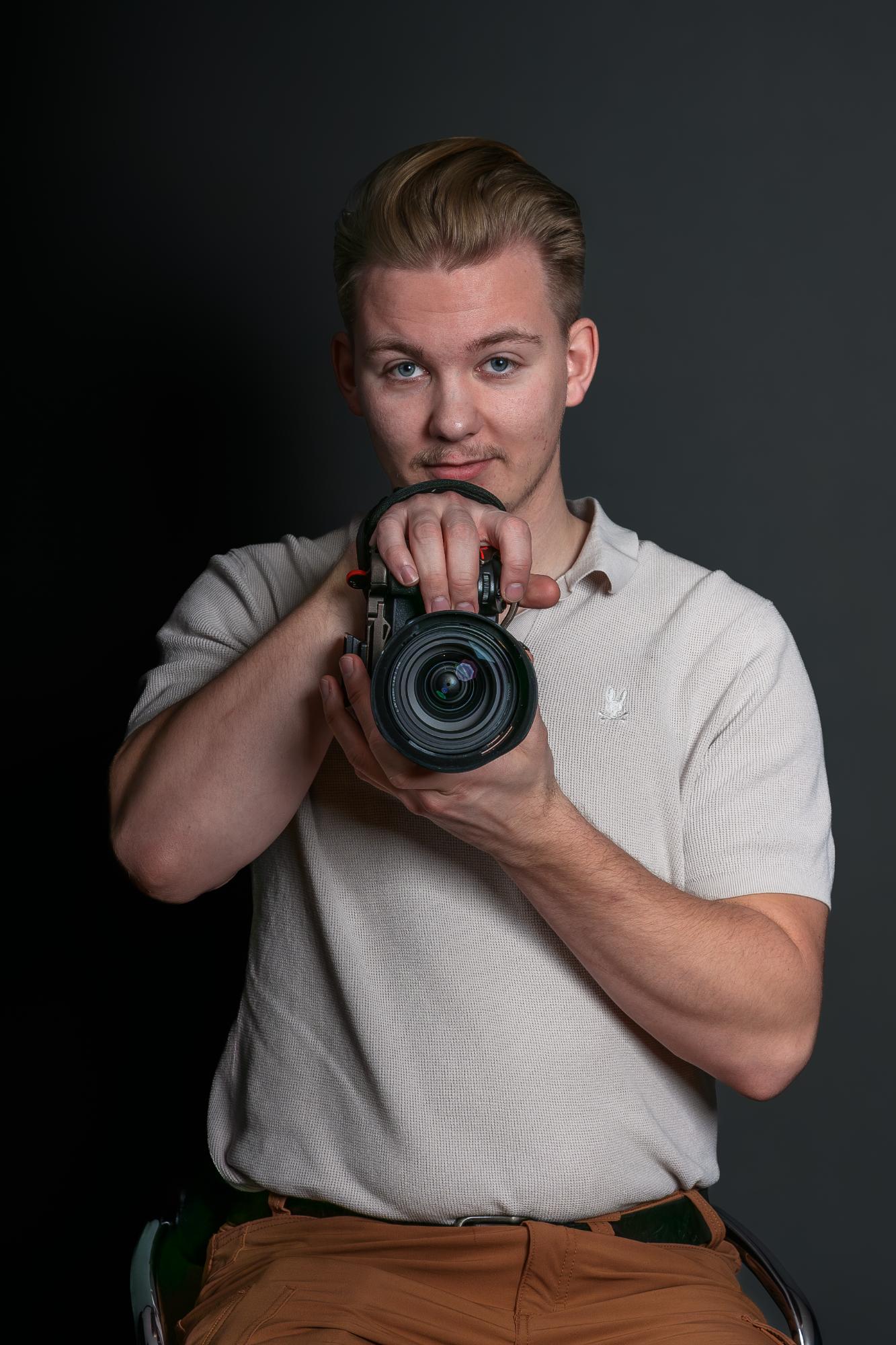 Intercept Photography photographer holding a camera, studio headshot